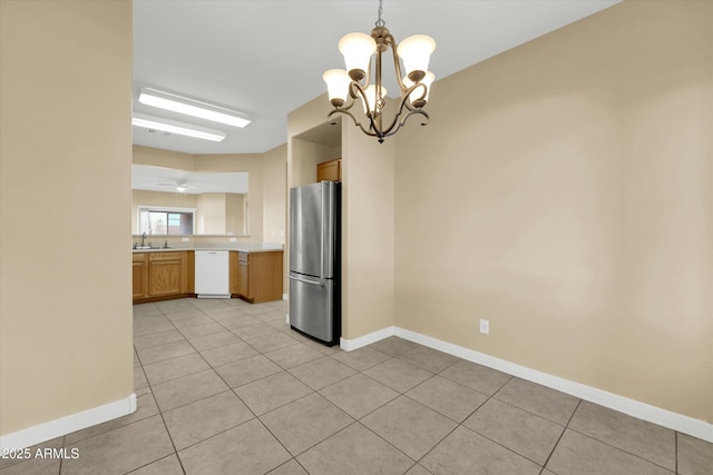 kitchen with light tile patterned floors, stainless steel fridge, white dishwasher, and decorative light fixtures