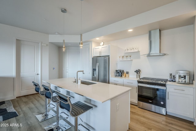 kitchen featuring sink, appliances with stainless steel finishes, white cabinetry, hanging light fixtures, and wall chimney exhaust hood