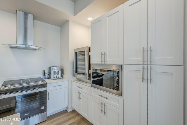 kitchen with built in microwave, stainless steel gas range oven, white cabinets, and range hood