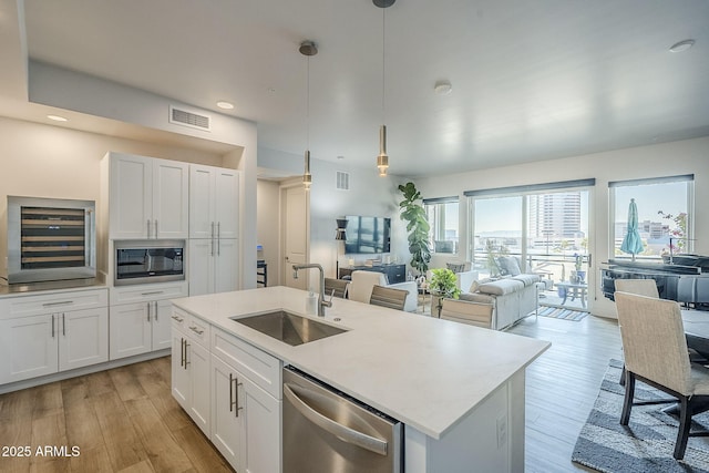 kitchen featuring sink, dishwasher, pendant lighting, beverage cooler, and white cabinets