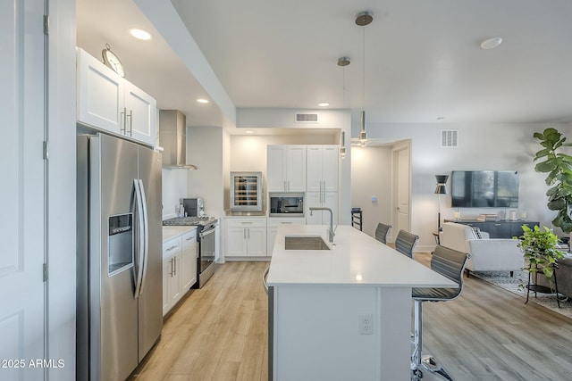 kitchen featuring a kitchen bar, sink, white cabinetry, pendant lighting, and stainless steel appliances