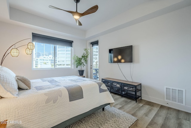 bedroom featuring hardwood / wood-style floors, a tray ceiling, and ceiling fan