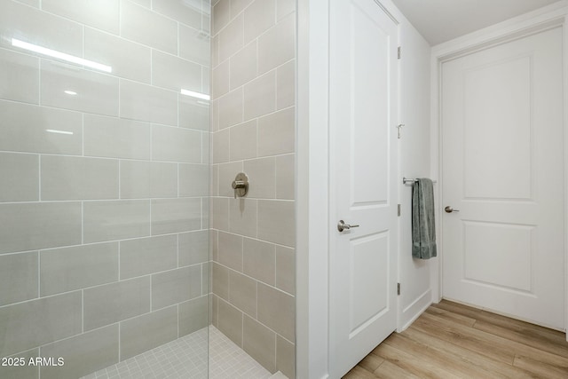 bathroom featuring hardwood / wood-style floors and a tile shower