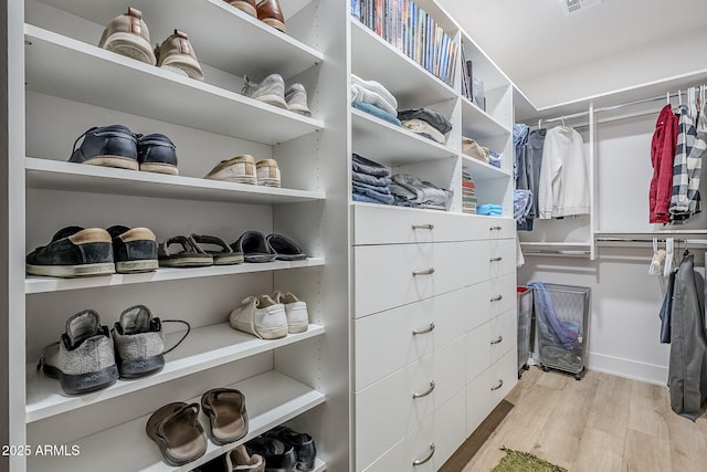 walk in closet with light hardwood / wood-style floors