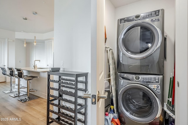 washroom with stacked washer / dryer, sink, and light wood-type flooring