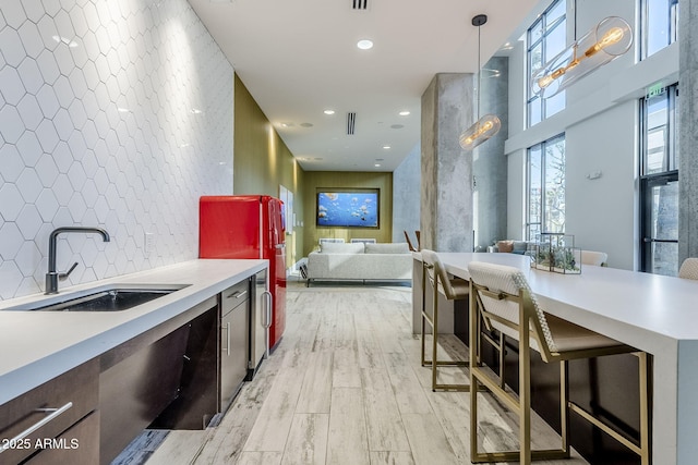 kitchen with pendant lighting, light hardwood / wood-style floors, sink, and backsplash