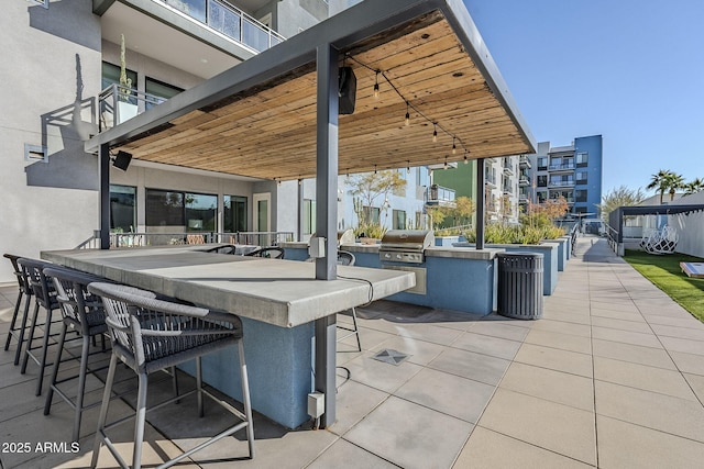 view of patio with exterior kitchen, a grill, and an outdoor bar