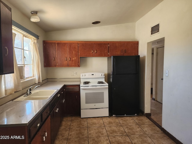 kitchen with white range with electric cooktop, light countertops, visible vents, freestanding refrigerator, and a sink