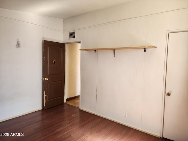 spare room featuring visible vents, dark wood finished floors, and baseboards