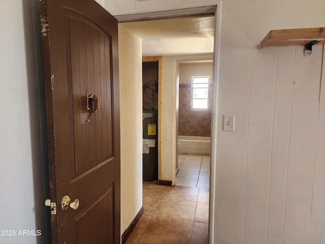 corridor featuring water heater and light tile patterned flooring