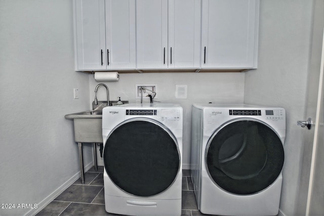 laundry area featuring cabinets, dark tile patterned floors, and washer and clothes dryer