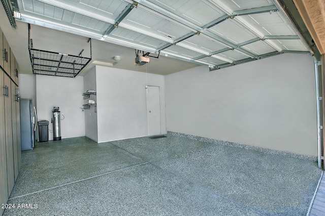 garage with a garage door opener and stainless steel fridge