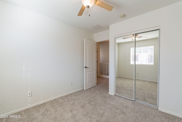 unfurnished bedroom featuring light carpet, a closet, and ceiling fan