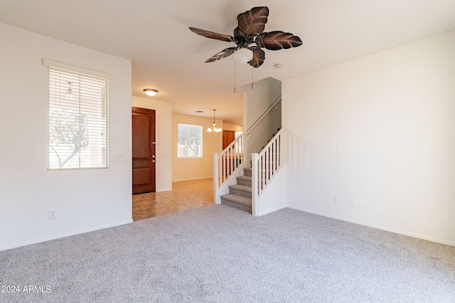 spare room featuring light carpet and ceiling fan with notable chandelier