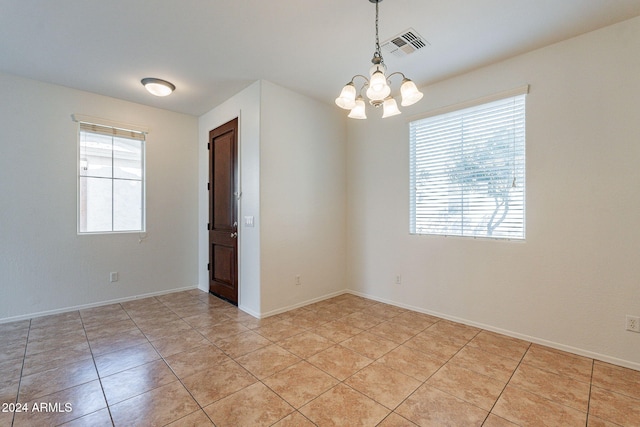 empty room featuring light tile patterned floors and a chandelier