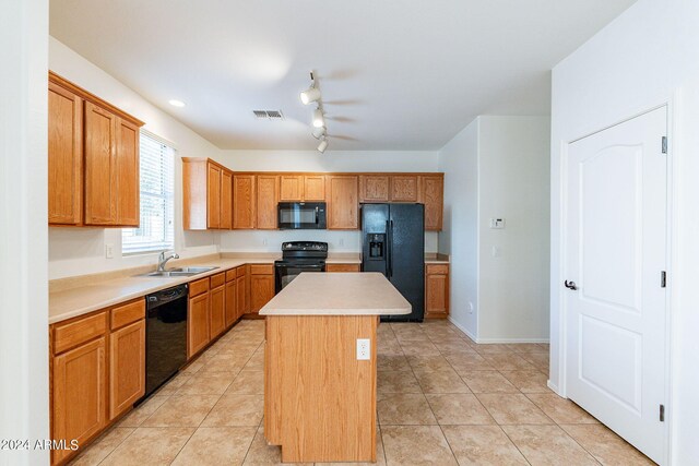 kitchen featuring black appliances, a center island, light tile patterned floors, and sink