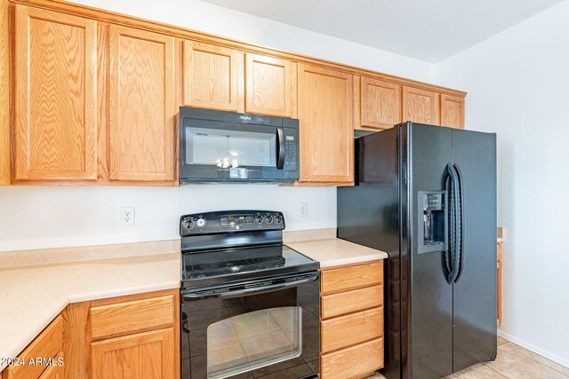 kitchen with light tile patterned flooring, a chandelier, and black appliances