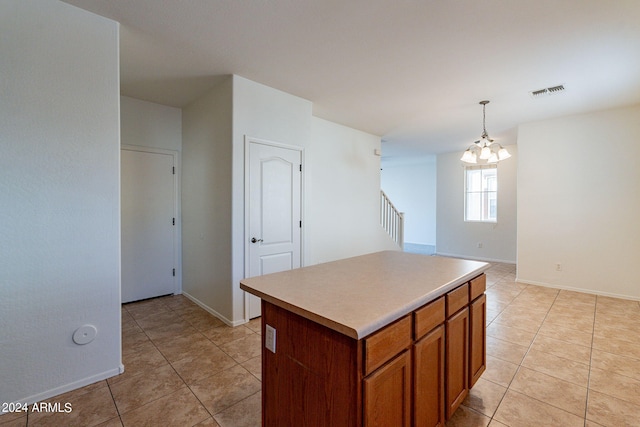 kitchen with light tile patterned floors, decorative light fixtures, a kitchen island, and a notable chandelier