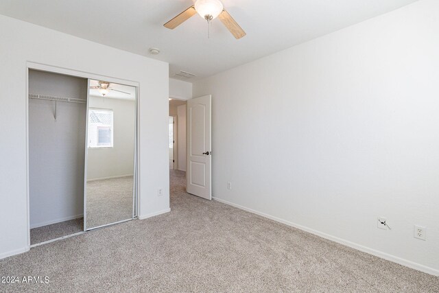 unfurnished bedroom with ceiling fan, a closet, and light carpet