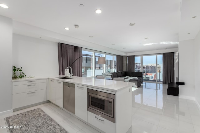 kitchen with stainless steel appliances, white cabinetry, sink, and kitchen peninsula