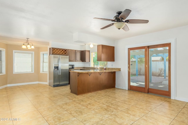 kitchen featuring kitchen peninsula, light tile patterned floors, ceiling fan with notable chandelier, and stainless steel refrigerator with ice dispenser