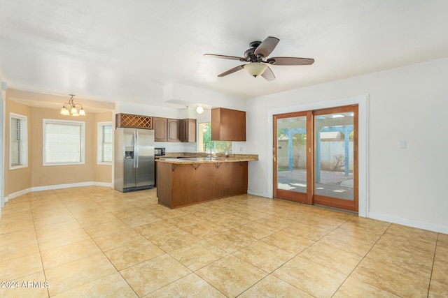 kitchen with kitchen peninsula, stainless steel fridge with ice dispenser, light tile patterned floors, and ceiling fan with notable chandelier