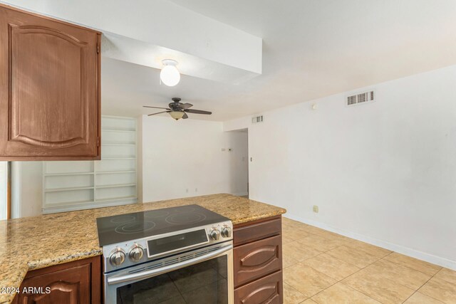 kitchen with light stone counters, ceiling fan, light tile patterned flooring, and stainless steel electric range