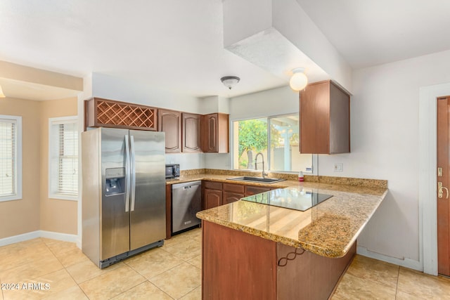 kitchen with kitchen peninsula, light stone counters, sink, black appliances, and light tile patterned flooring