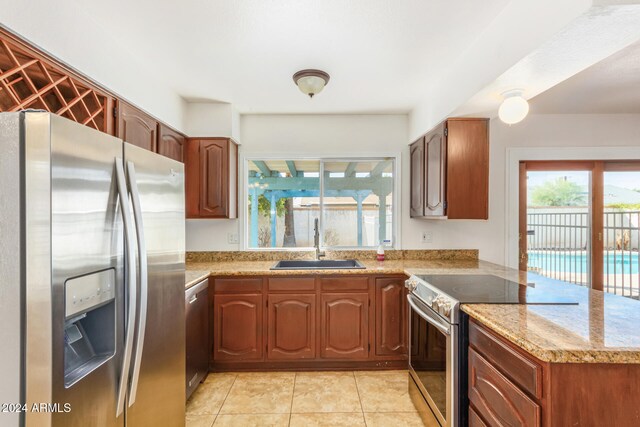 kitchen featuring sink, light tile patterned floors, light stone counters, kitchen peninsula, and stainless steel appliances