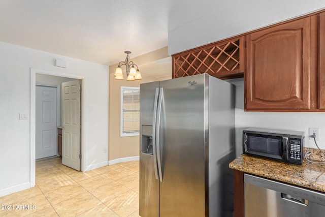 kitchen featuring appliances with stainless steel finishes, decorative light fixtures, stone countertops, a notable chandelier, and light tile patterned flooring