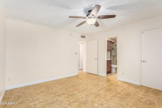 unfurnished bedroom featuring a walk in closet, a textured ceiling, ceiling fan, and connected bathroom