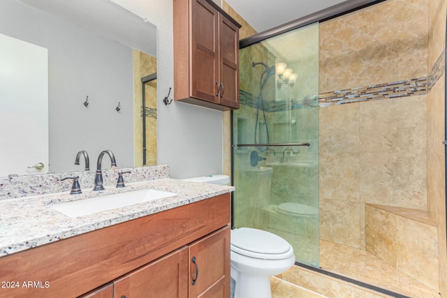 bathroom featuring tile patterned flooring, vanity, a shower with shower door, and toilet