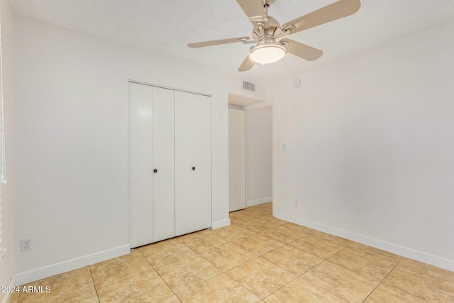 unfurnished bedroom with ceiling fan, light tile patterned floors, and a closet