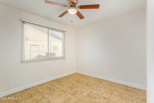 empty room with ceiling fan, light tile patterned floors, and a textured ceiling