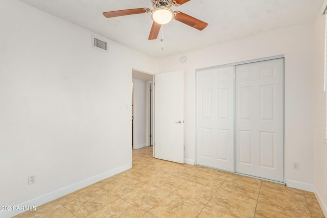 unfurnished bedroom with light tile patterned floors, a textured ceiling, a closet, and ceiling fan