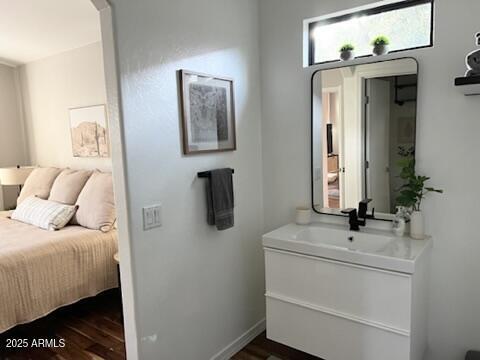 bathroom featuring wood finished floors, vanity, ensuite bath, and baseboards