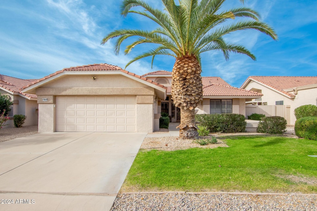 mediterranean / spanish house with a front lawn and a garage