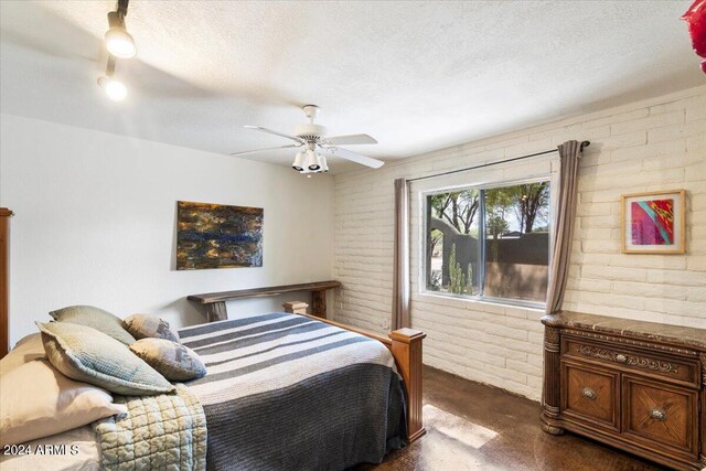 bedroom featuring brick wall, a textured ceiling, and ceiling fan