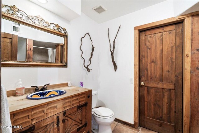 bathroom featuring curtained shower, vanity, toilet, and tile patterned floors