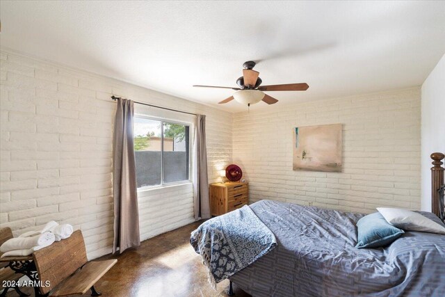 bedroom with ceiling fan and brick wall