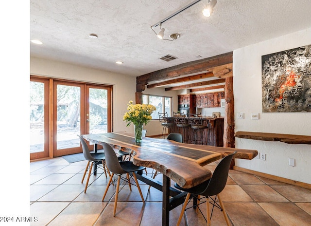 dining area with light tile patterned floors, a textured ceiling, french doors, and rail lighting