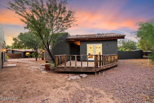 back house at dusk featuring a wooden deck and french doors