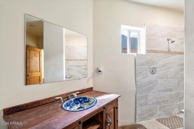 bathroom with a tile shower and vanity