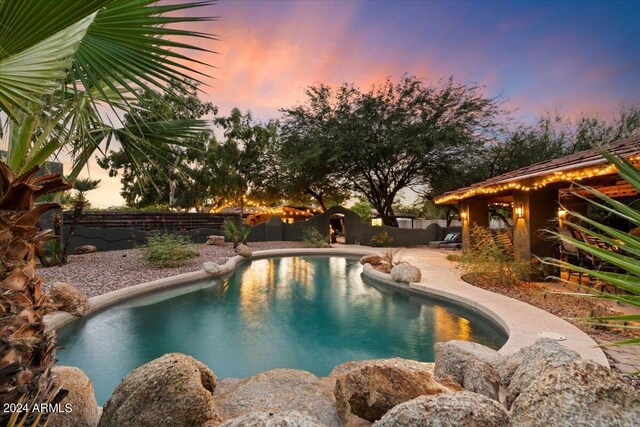 pool at dusk featuring a patio area