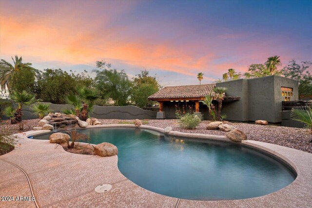 pool at dusk featuring a patio area