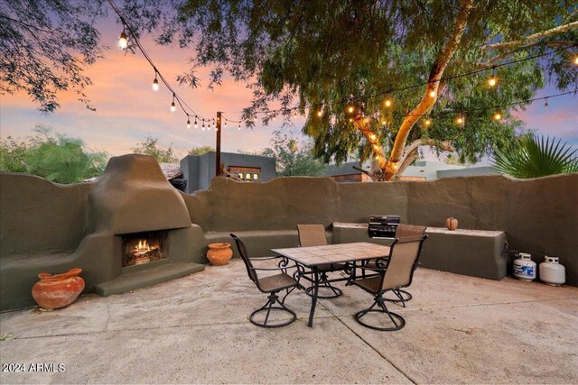 patio terrace at dusk featuring exterior fireplace