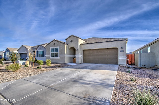 view of front of home with a garage, driveway, a tiled roof, fence, and stucco siding