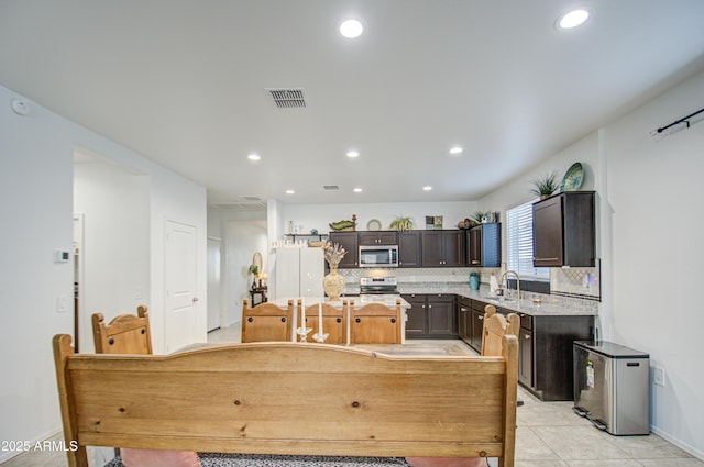 kitchen featuring stainless steel appliances, a sink, backsplash, and a kitchen island