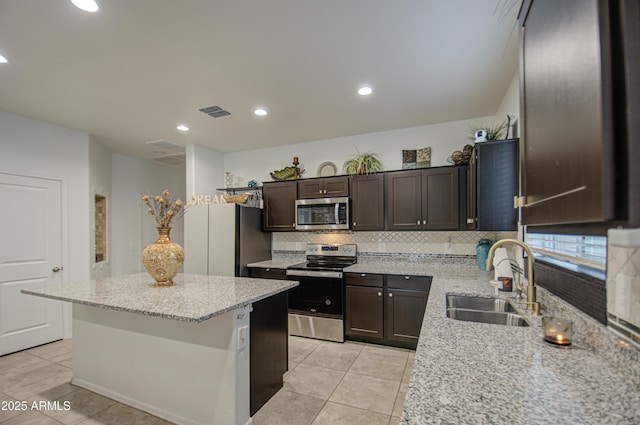 kitchen with visible vents, decorative backsplash, a kitchen island, appliances with stainless steel finishes, and a sink