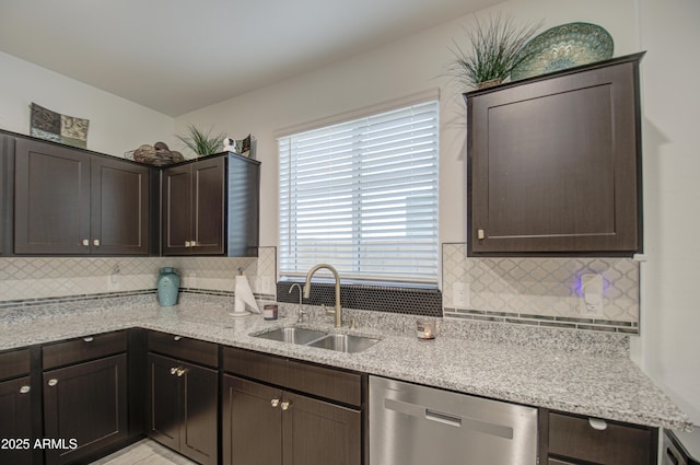 kitchen with dark brown cabinetry, decorative backsplash, dishwasher, light stone counters, and a sink